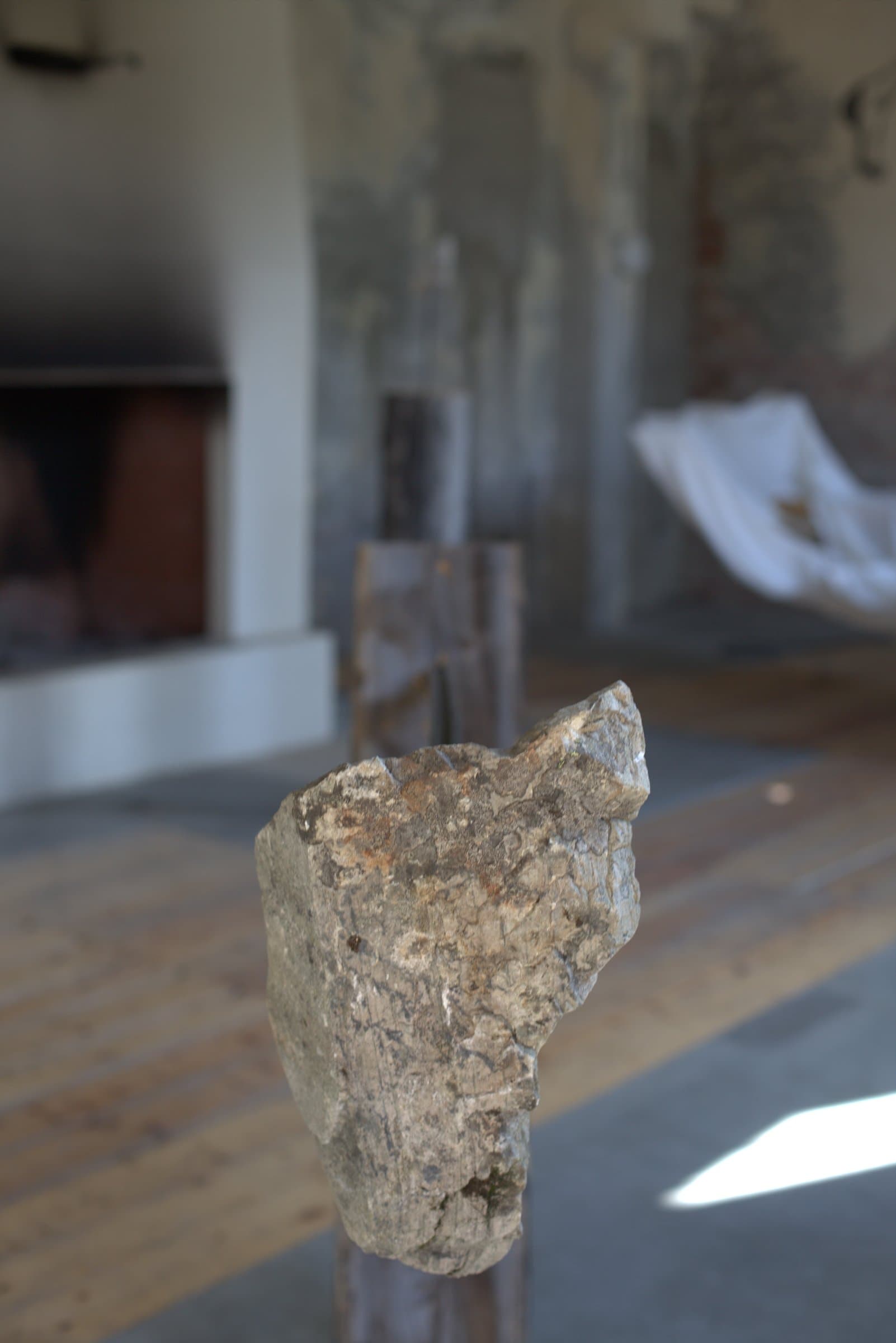 Close-up of the stone balanced on top of the metal rod, the room blurred behind it