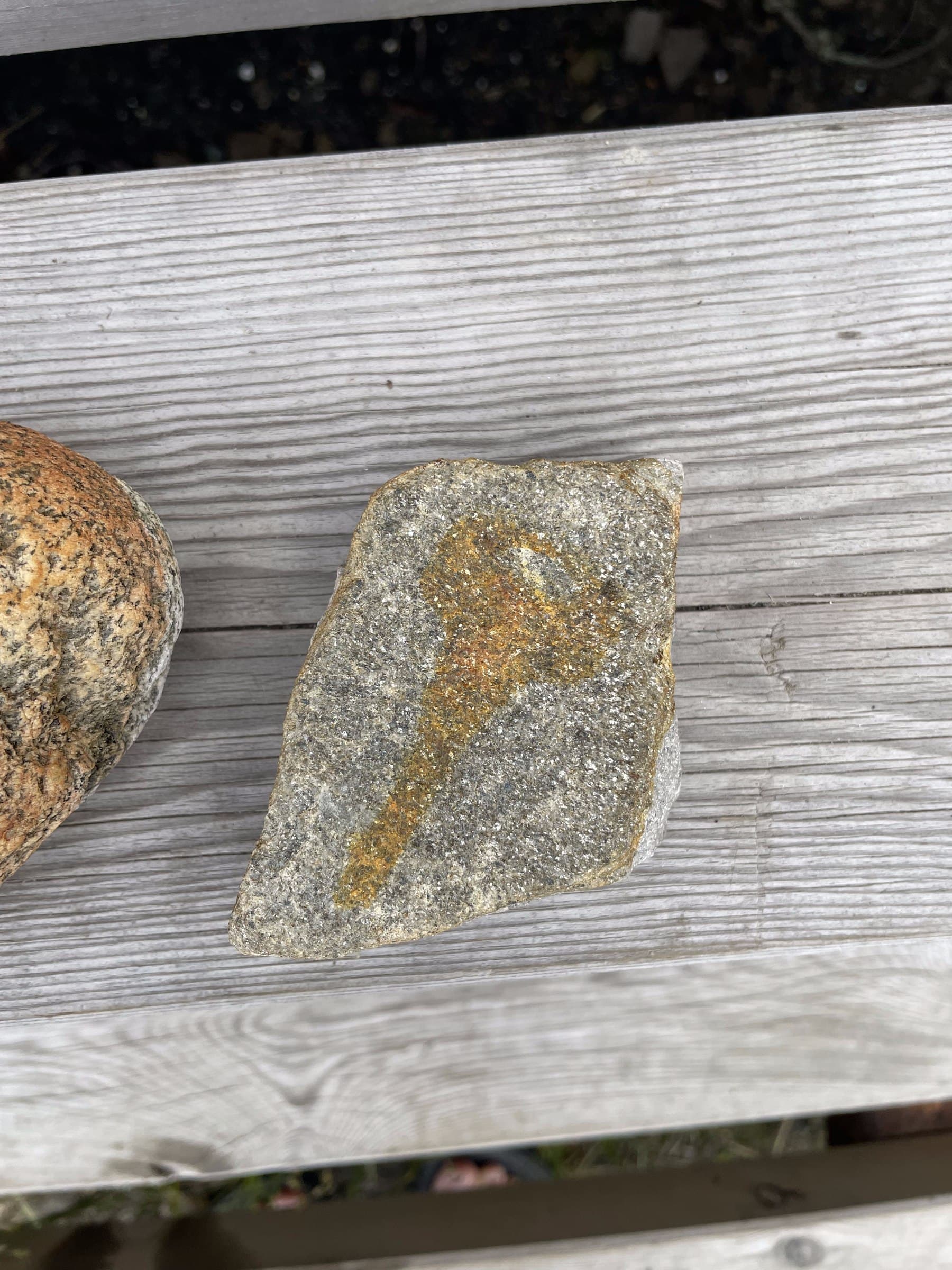Close-up of a stone marked with a rust-colored key shape, its granite surface glittering with mica