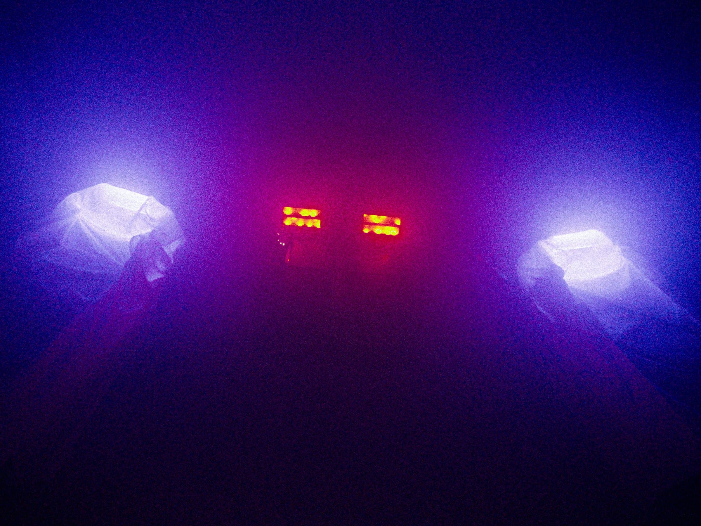 Purple haze with two draped white fabric forms on either side and a lit mixing desk glowing red and yellow in the center