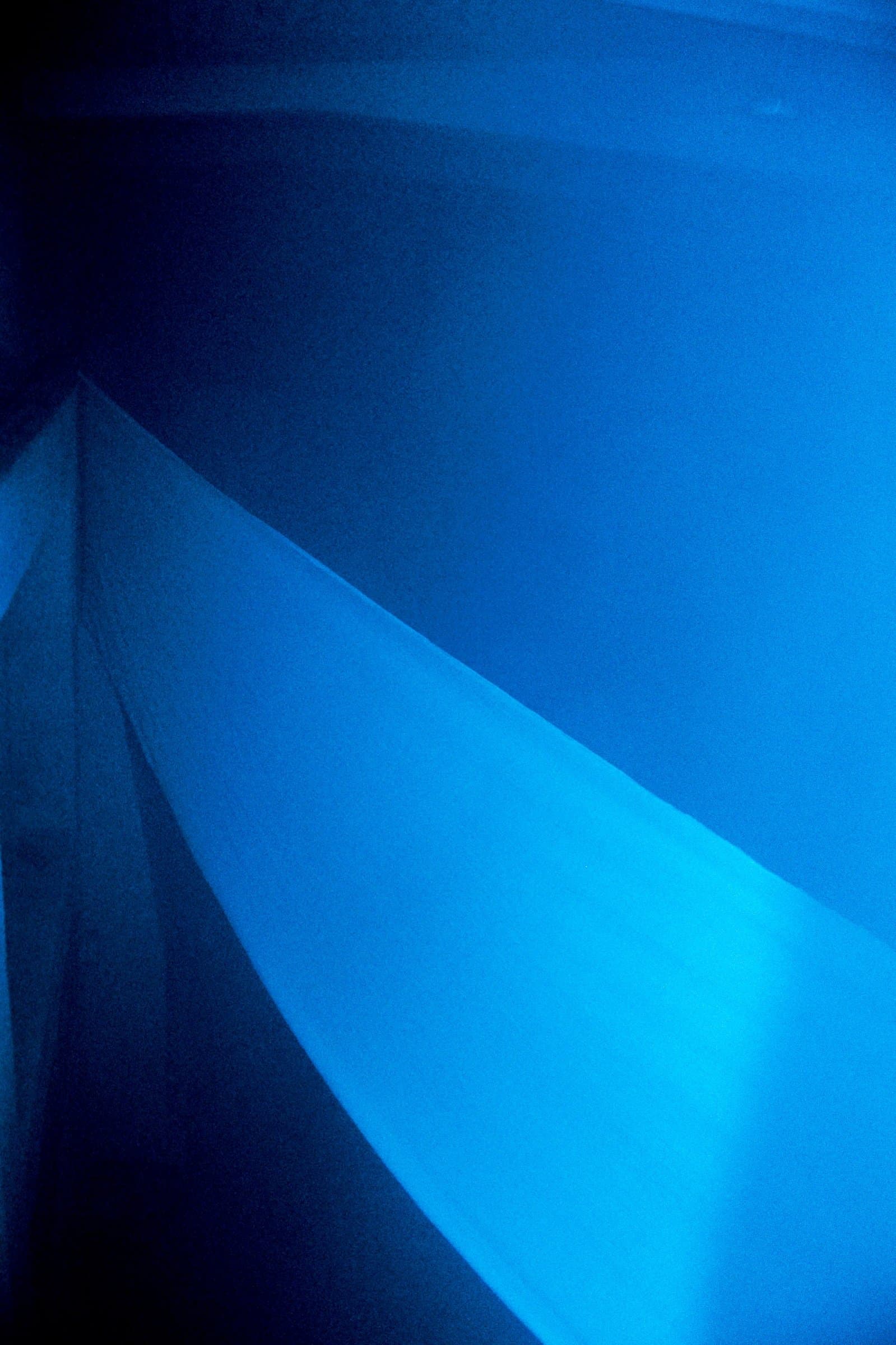 Looking up at blue-lit draped fabric sails from a second angle