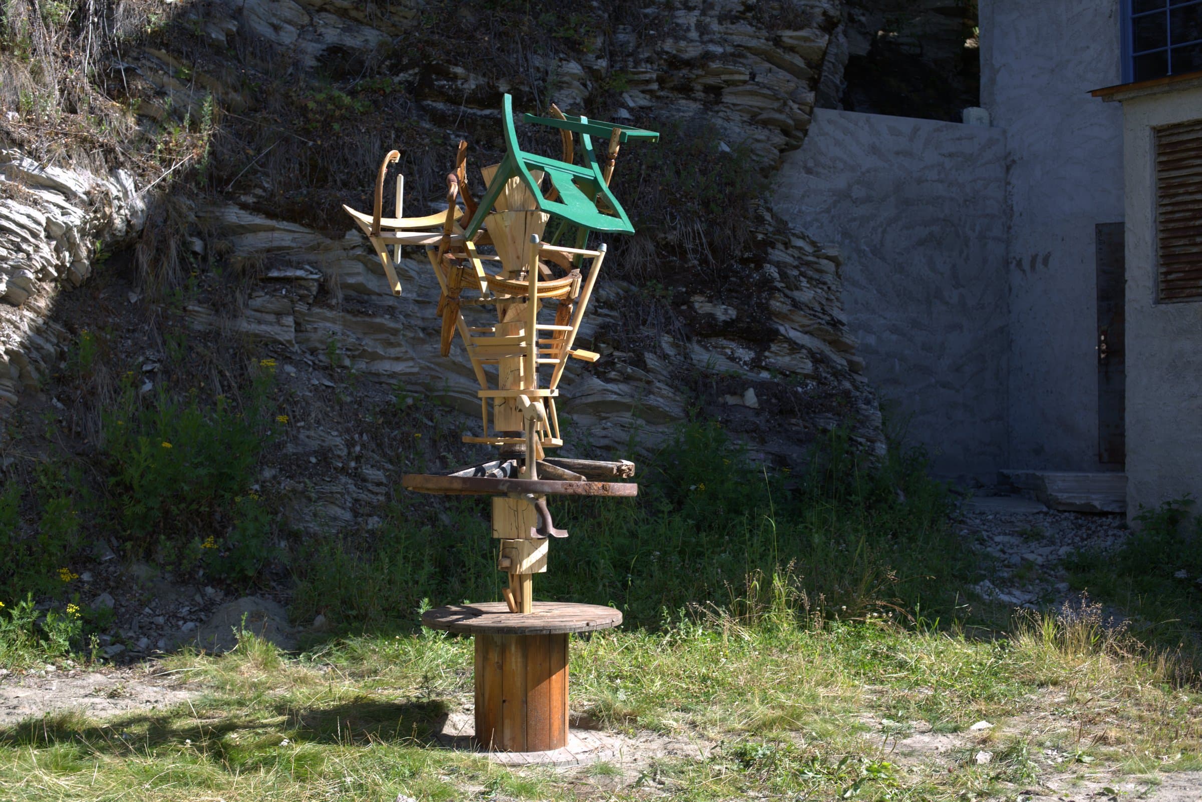The same stacked-chair sculpture seen from further back, with the power plant building visible alongside it