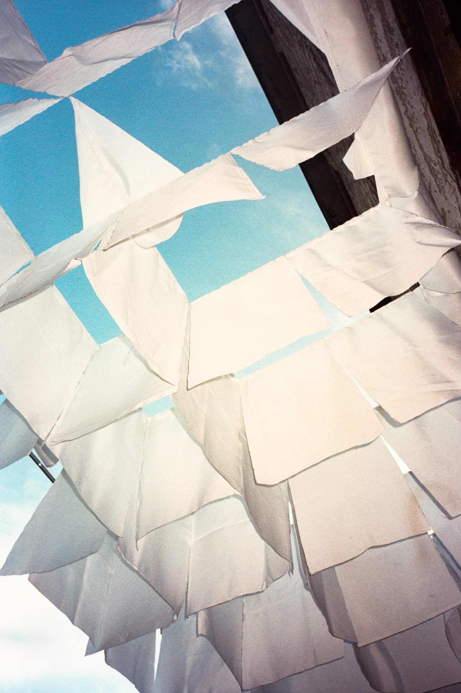 The same view looking straight up at the fabric flags against a blue sky, in color
