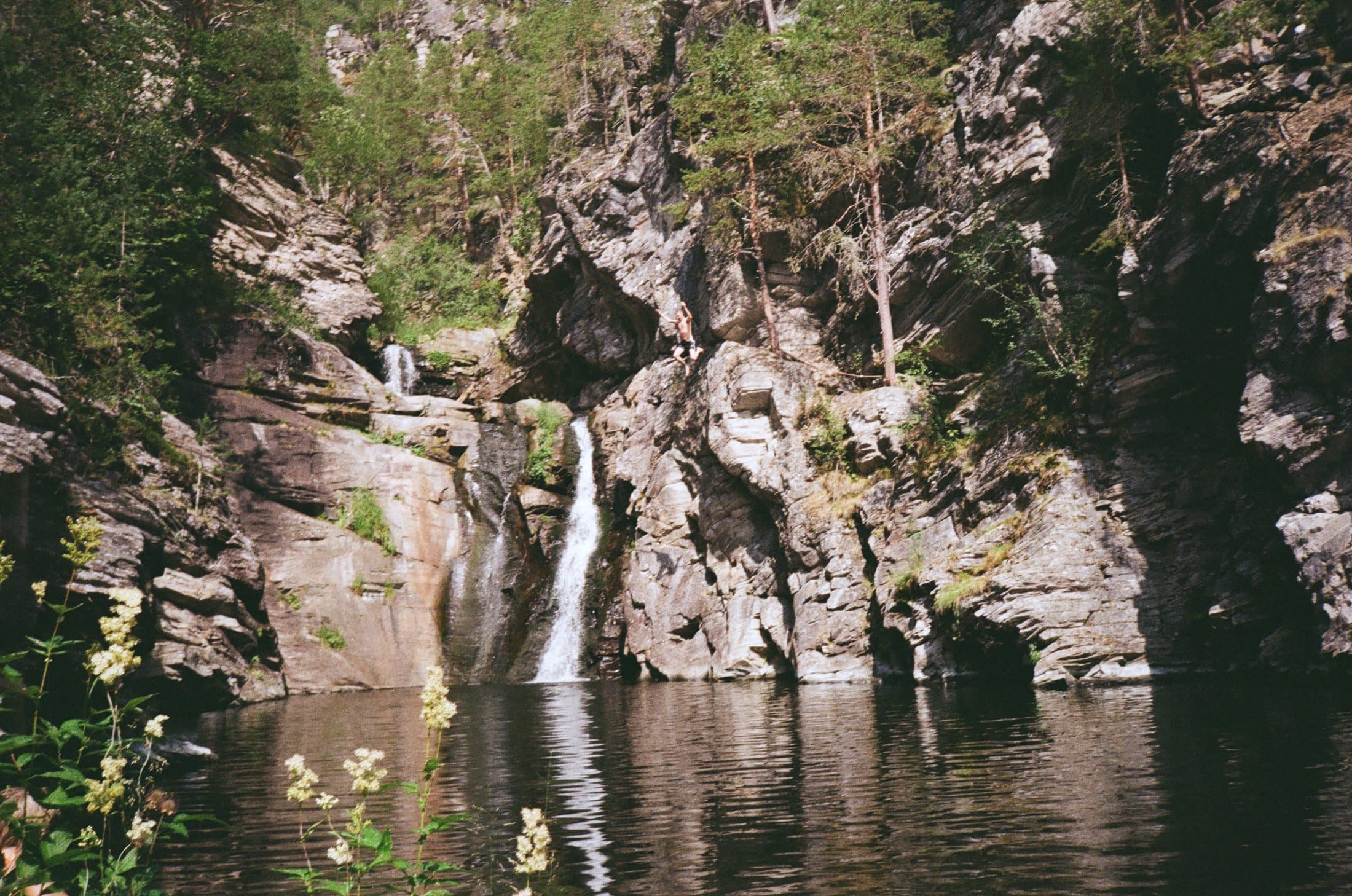 A waterfall falling into a dark pool between rock walls.