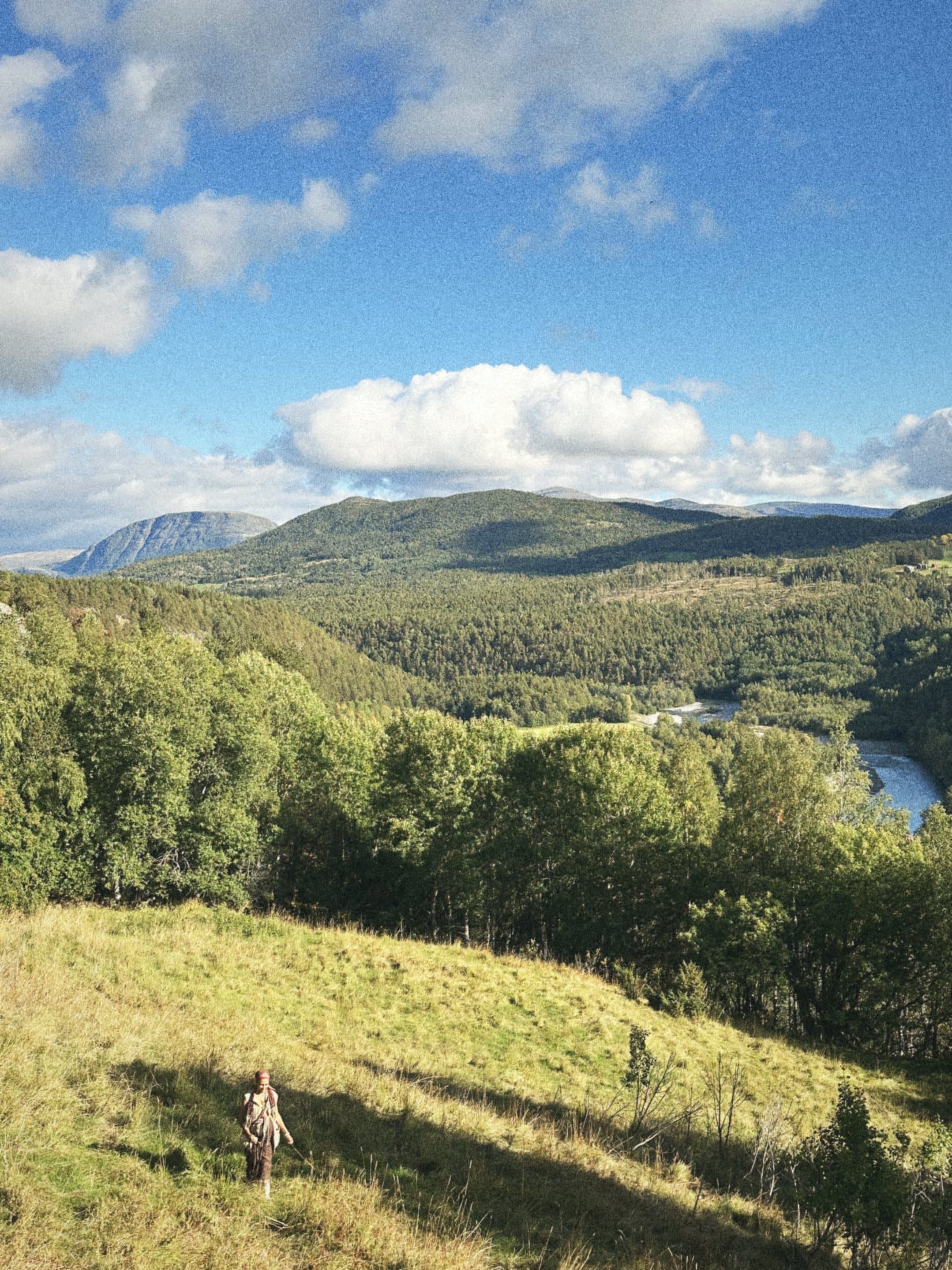 Green hills falling away to the river valley under a blue sky.